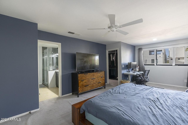 carpeted bedroom featuring a walk in closet, connected bathroom, a closet, and ceiling fan