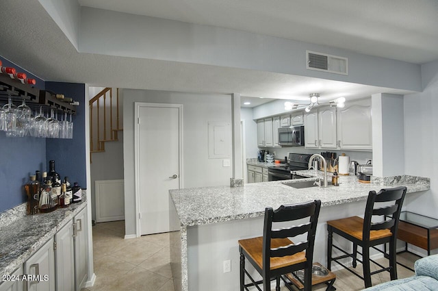 kitchen with kitchen peninsula, a kitchen breakfast bar, black range with electric stovetop, and sink