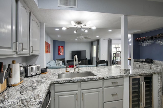 kitchen featuring kitchen peninsula, white cabinetry, sink, and beverage cooler