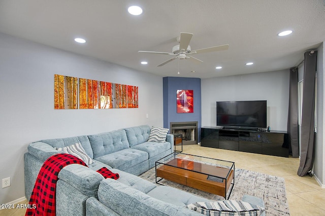 living room featuring ceiling fan, light tile patterned flooring, and a fireplace