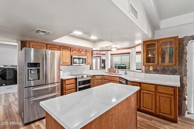 1024 E Saddle Mountain Rd, Phoenix, AZ 85086 - kitchen with appliances with stainless steel finishes, washer / dryer, a raised ceiling, a sink, and light wood finished floors