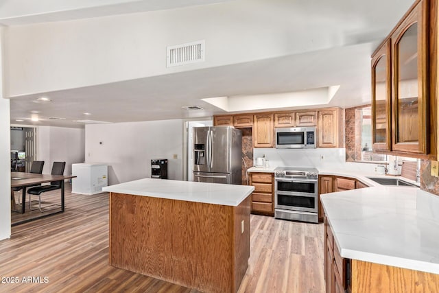 1024 E Saddle Mountain Rd, Phoenix, AZ 85086 - kitchen with appliances with stainless steel finishes, light wood-type flooring, a center island, glass insert cabinets, and light countertops