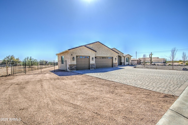 view of front of house featuring a garage, stone siding, fence, decorative driveway, and stucco siding