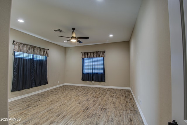 unfurnished room featuring a healthy amount of sunlight, visible vents, baseboards, and wood finished floors