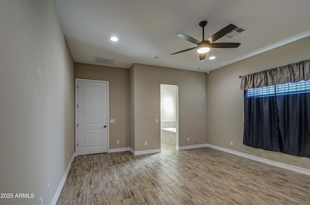 unfurnished room featuring ceiling fan, wood finished floors, visible vents, and baseboards