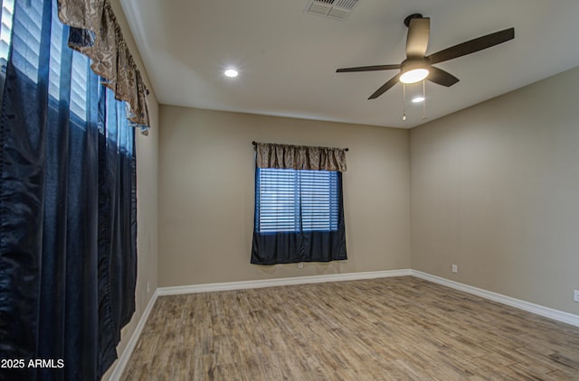 unfurnished room featuring a ceiling fan, baseboards, visible vents, and wood finished floors