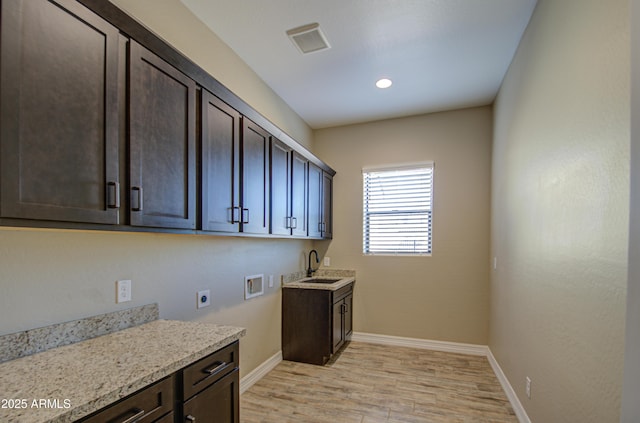 washroom featuring light wood finished floors, hookup for a washing machine, visible vents, cabinet space, and electric dryer hookup