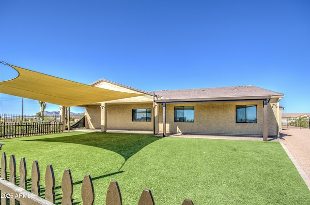 rear view of property with a patio, a lawn, fence, and stucco siding