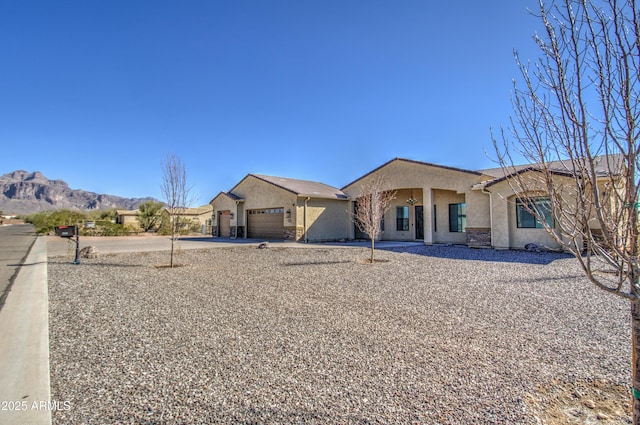 view of front of home featuring a mountain view, driveway, an attached garage, and stucco siding