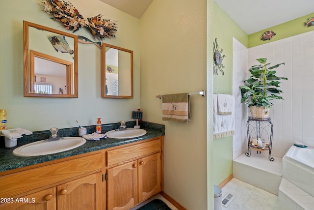 bathroom with tile patterned flooring, vanity, and a relaxing tiled tub