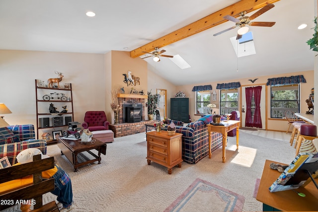 living room with vaulted ceiling with skylight, ceiling fan, a fireplace, and light carpet