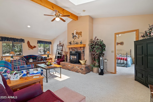 carpeted living room featuring vaulted ceiling with skylight, ceiling fan, and a wood stove