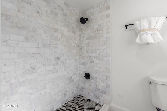 bathroom with a tile shower and toilet