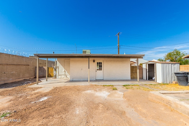 rear view of house featuring a storage shed