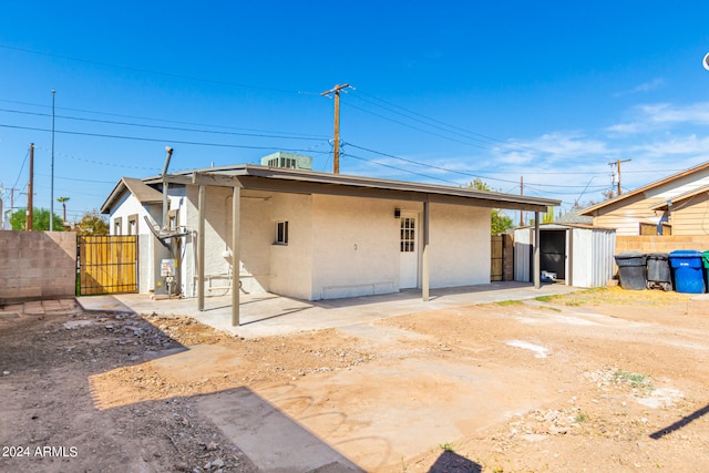 back of property featuring a storage shed and a patio area