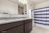 full bath featuring a chandelier, curtained shower, and vanity