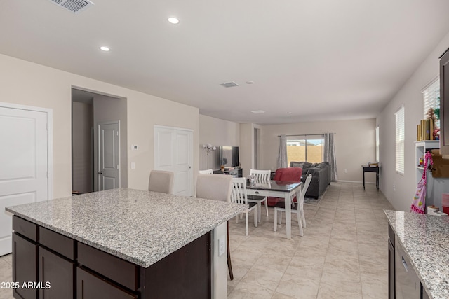 kitchen with dark brown cabinets, light stone counters, visible vents, and recessed lighting