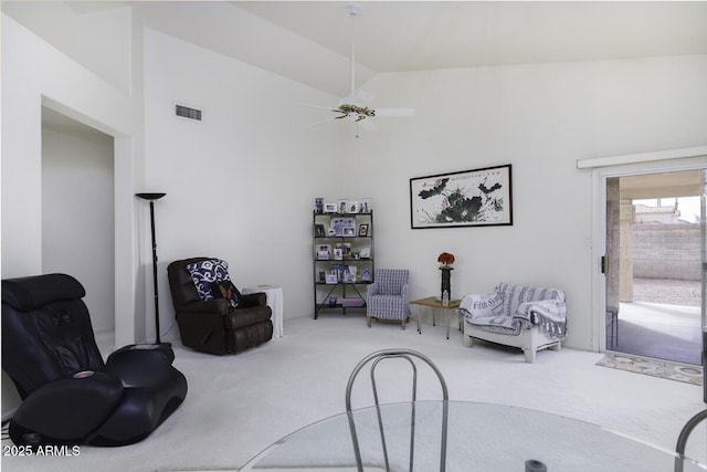 sitting room with carpet flooring, high vaulted ceiling, visible vents, and a ceiling fan