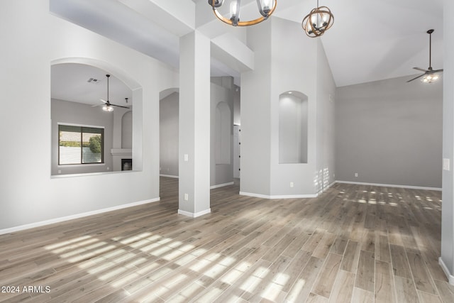 unfurnished living room featuring high vaulted ceiling, ceiling fan with notable chandelier, and hardwood / wood-style flooring