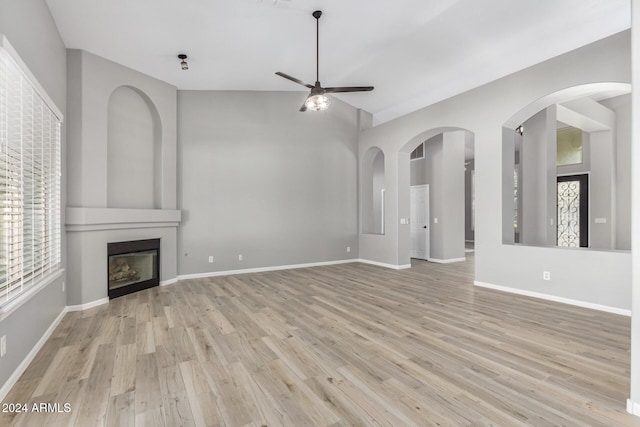 unfurnished living room with ceiling fan, a large fireplace, and light hardwood / wood-style flooring