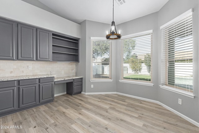 kitchen with light stone countertops, tasteful backsplash, light hardwood / wood-style flooring, decorative light fixtures, and gray cabinets