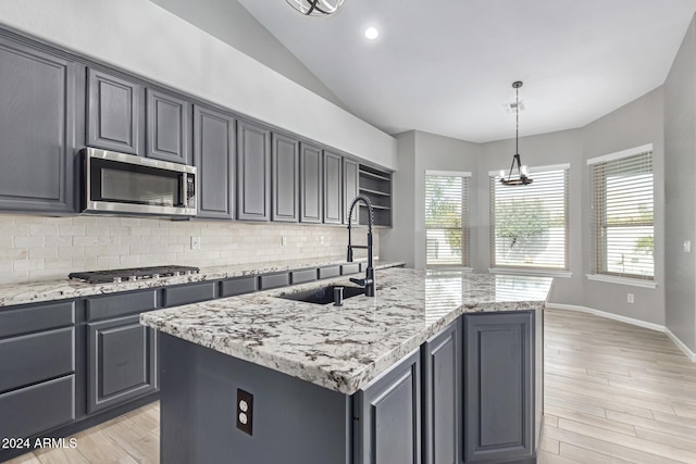 kitchen featuring decorative backsplash, pendant lighting, stainless steel appliances, and a center island with sink