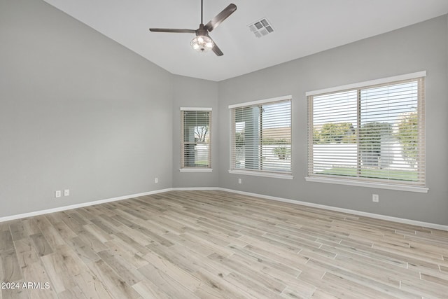 empty room featuring vaulted ceiling, a wealth of natural light, and light hardwood / wood-style flooring