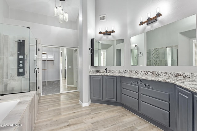 bathroom with a chandelier, wood-type flooring, vanity, and separate shower and tub