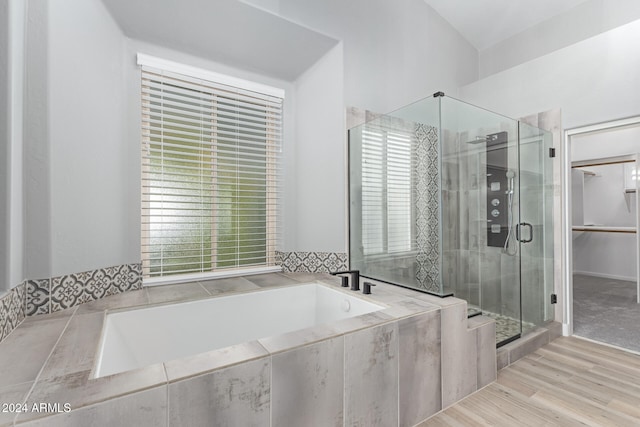 bathroom featuring wood-type flooring, independent shower and bath, and a healthy amount of sunlight