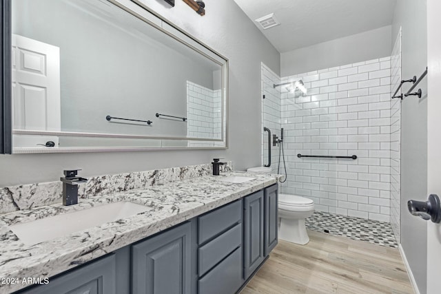 bathroom featuring tiled shower, vanity, hardwood / wood-style flooring, and toilet