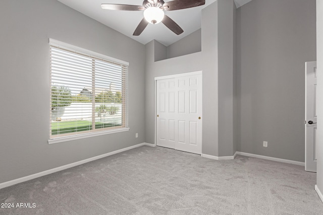 unfurnished bedroom featuring a closet, light colored carpet, vaulted ceiling, and ceiling fan