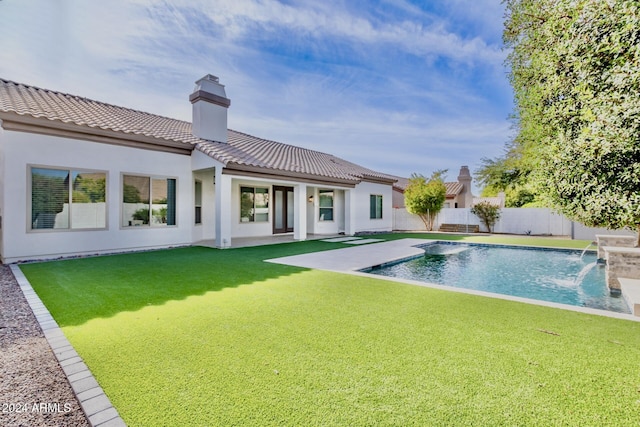 rear view of property with a fenced in pool, pool water feature, and a yard