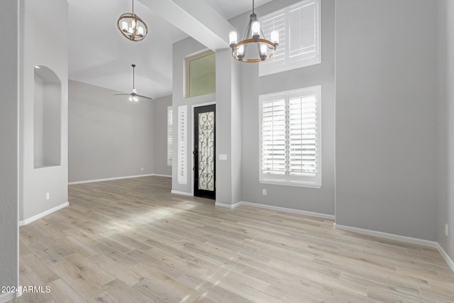 entrance foyer with ceiling fan with notable chandelier, light hardwood / wood-style floors, and a towering ceiling