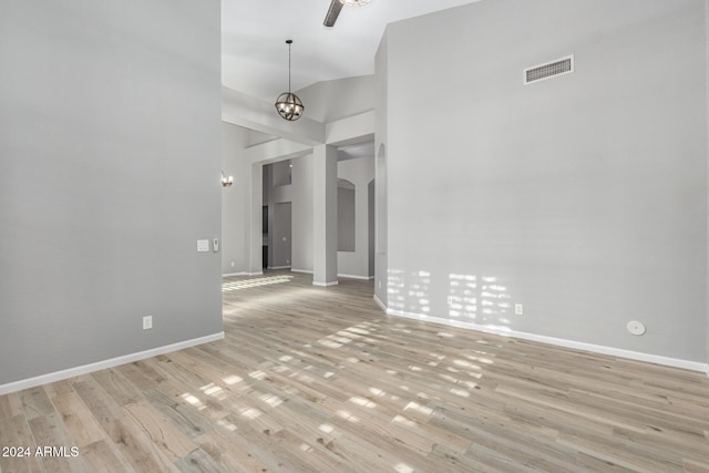 spare room with light hardwood / wood-style flooring, a towering ceiling, and a notable chandelier