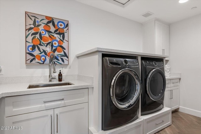 clothes washing area with cabinets, separate washer and dryer, parquet flooring, and sink