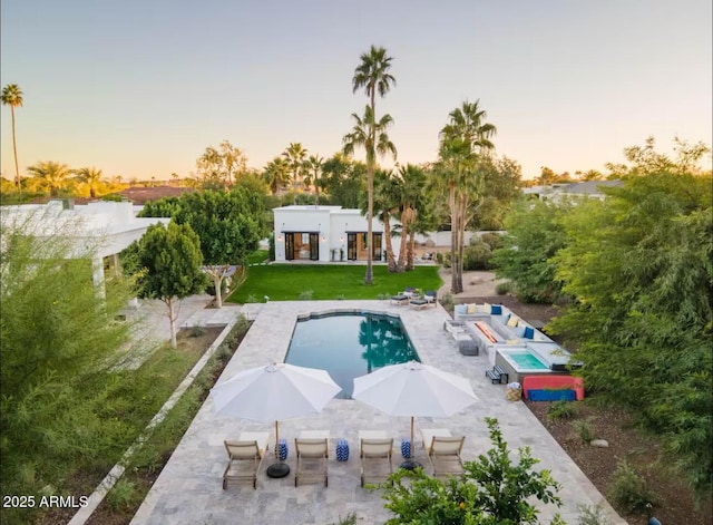 pool at dusk with a yard and a patio