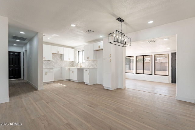 kitchen featuring open floor plan, light countertops, visible vents, and white cabinets