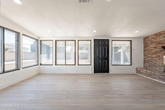 interior space featuring light wood-style flooring, visible vents, a textured ceiling, and recessed lighting