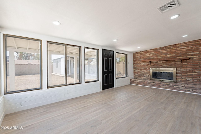 unfurnished living room featuring plenty of natural light, light wood-style flooring, a fireplace, and visible vents