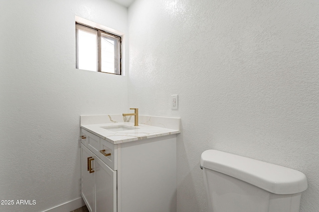 bathroom with toilet, a textured wall, and vanity