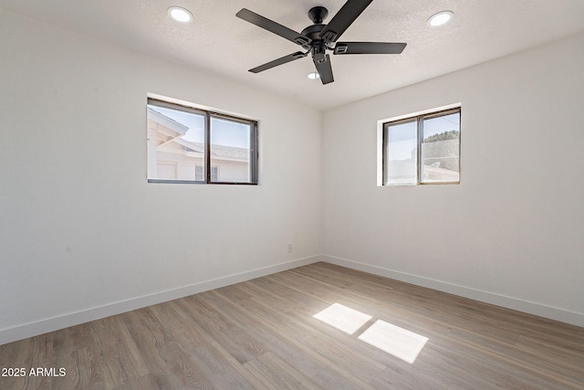 spare room featuring baseboards, a wealth of natural light, and wood finished floors