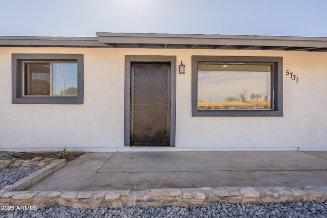 view of exterior entry with a patio and stucco siding