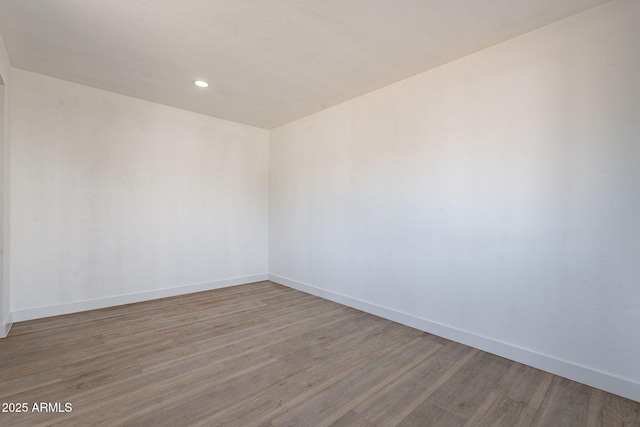 unfurnished room with baseboards, wood finished floors, and recessed lighting