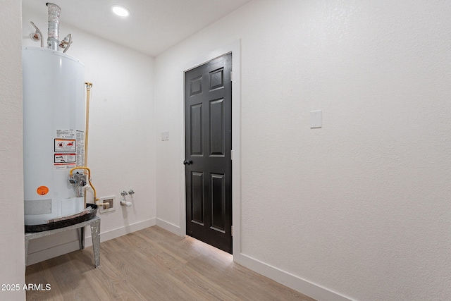 entryway with gas water heater, light wood-style flooring, and baseboards