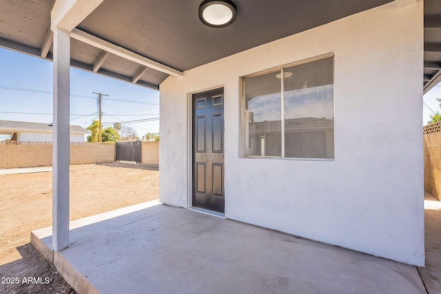 doorway to property with a patio area, fence, and stucco siding