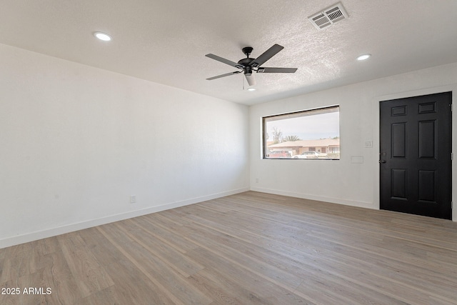 empty room featuring visible vents, light wood-style flooring, and baseboards