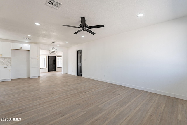 unfurnished living room with baseboards, light wood-style flooring, visible vents, and a ceiling fan