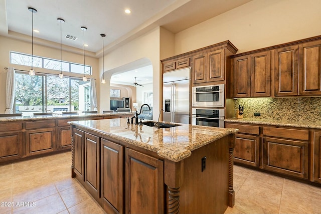 kitchen with tasteful backsplash, visible vents, appliances with stainless steel finishes, light stone countertops, and a sink