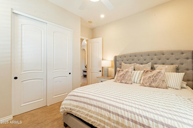 carpeted bedroom featuring a ceiling fan, arched walkways, and a closet