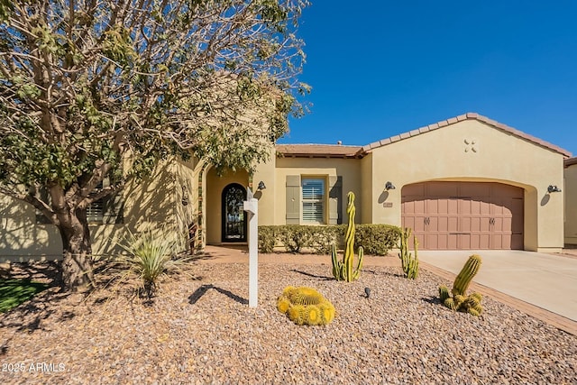 mediterranean / spanish home featuring driveway, an attached garage, and stucco siding